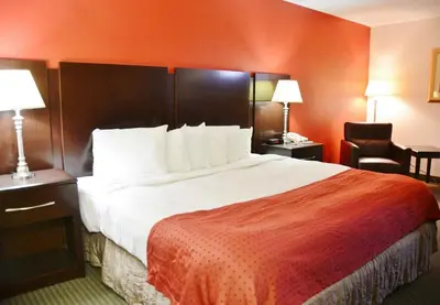 a hotel room with a large bed and a chair at Country Hearth Inn & Suites - Kenton in Kenton