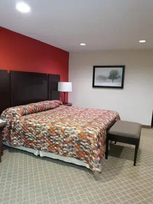 a bedroom with a bed and a lamp and a chair at Country Hearth Inn & Suites - Kenton in Kenton