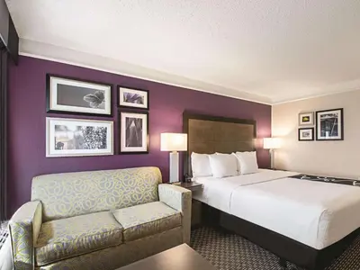 a hotel room with a bed and a chair at La Quinta by Wyndham Cincinnati Sharonville in Sharonville
