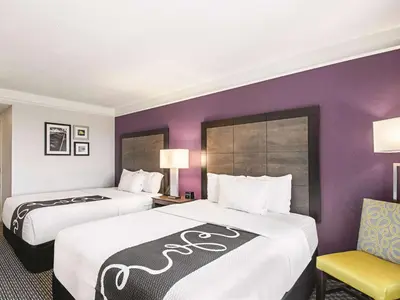 two beds in a hotel room with purple walls at La Quinta by Wyndham Cincinnati Sharonville in Sharonville