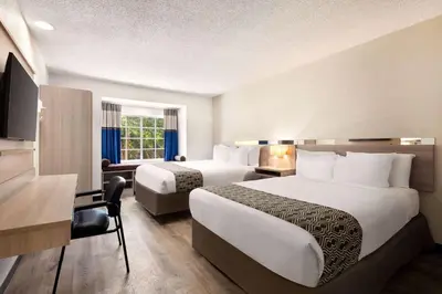 a hotel room with two beds and a desk at Microtel Inn & Suites by Wyndham Florence/Cincinnati Airpo in Florence