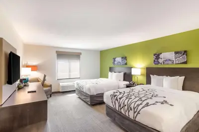a hotel room with two beds and a flat screen tv at Sleep Inn Logan Ohio-Hocking Hills in Logan