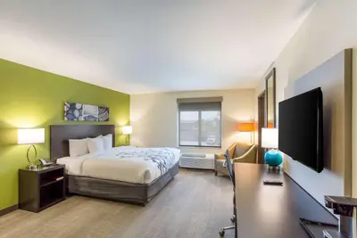 a hotel room with a bed and a flat screen tv at Sleep Inn Logan Ohio-Hocking Hills in Logan
