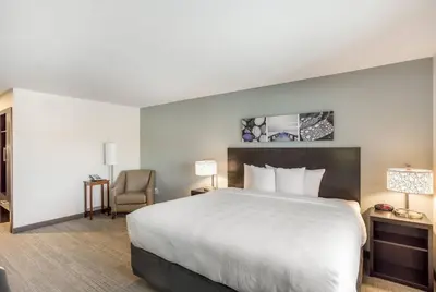 a hotel room with a large bed and a chair at MainStay Suites Logan Ohio-Hocking Hills in Logan