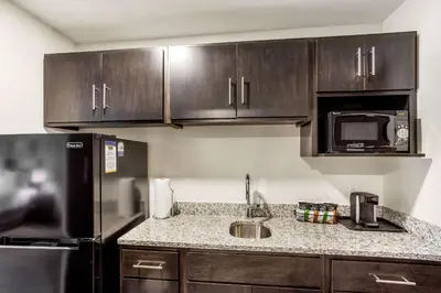 a kitchen with wooden cabinets and a black refrigerator at MainStay Suites Logan Ohio-Hocking Hills in Logan