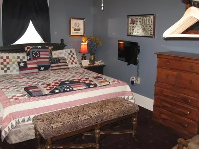 a bedroom with a bed with a dresser and a television at Bayberry House Bed and Breakfast in Steubenville