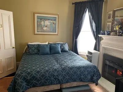 a bedroom with a bed with blue comforter and a fireplace at Bayberry House Bed and Breakfast in Steubenville