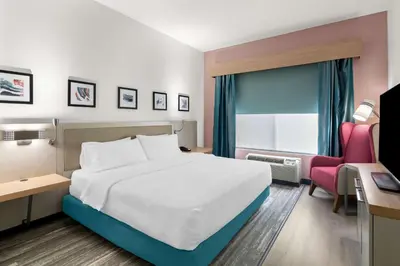 a bedroom with a white bed and a pink chair at Hilton Garden Inn Lexington Georgetown in Georgetown