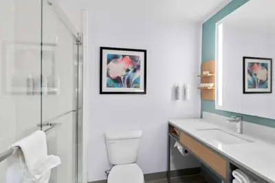 a bathroom with a toilet and a sink and a mirror at Hilton Garden Inn Lexington Georgetown in Georgetown