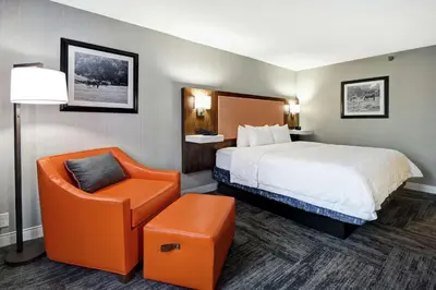 a hotel room with a bed and an orange chair at Hampton Inn Lexington I-75 in Lexington