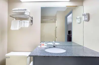 a bathroom with a sink and a toilet and a mirror at Super 8 by Wyndham Harrison OH in Harrison