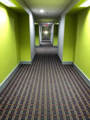 an empty hallway in an office building with green walls at Super 8 by Wyndham Harrison OH in Harrison