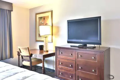 a hotel room with a television on a dresser with a desk at Baymont Inn and Suites by Wyndham Columbus / Near OSU in Columbus