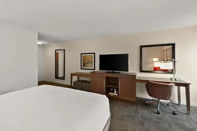 a hotel room with a bed and a desk with a television at Hampton Inn Lancaster in Lancaster