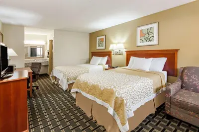 a hotel room with two beds and a chair at Days Inn by Wyndham Kent - Akron in Kent