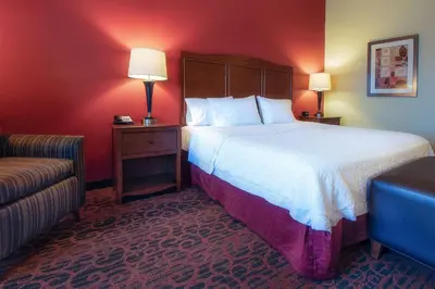 a hotel room with a large bed and a chair at Hampton Inn Oxford/Miami University Area in Oxford