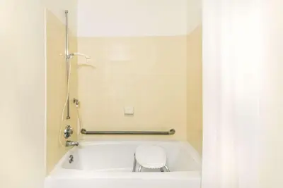 a bathroom with a bath tub with a toilet at Super 8 by Wyndham Twinsburg/Cleveland Area in Twinsburg