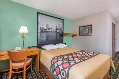 a hotel room with a bed and a desk and a table and chair at Super 8 by Wyndham Twinsburg/Cleveland Area in Twinsburg