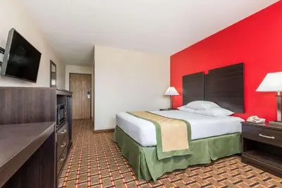 a hotel room with a bed with a red wall at Days Inn by Wyndham Muncie -Ball State University in Muncie
