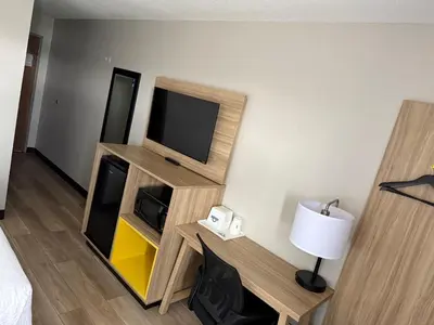 a room with a television and a desk with a lamp at Days Inn by Wyndham Muncie -Ball State University in Muncie