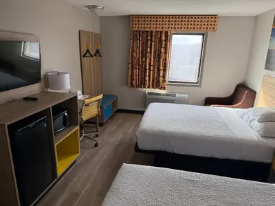 a hotel room with two beds and a flat screen tv at Days Inn by Wyndham Muncie -Ball State University in Muncie