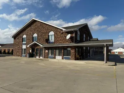 a large brick building with a parking lot at Days Inn by Wyndham Muncie -Ball State University in Muncie
