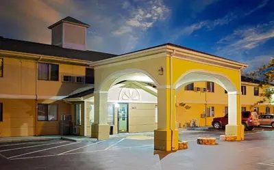 a yellow building with an archway in a parking lot at Super 8 by Wyndham Muncie/Ball St. College Area in Muncie