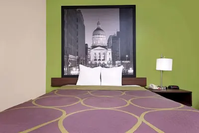 a bedroom with a bed with a picture of a building at Super 8 by Wyndham Muncie/Ball St. College Area in Muncie