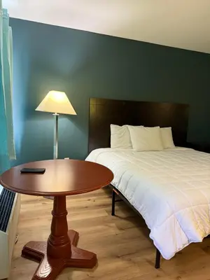 a bedroom with a bed and a table with a lamp at Country Club Inn & Suites in Fostoria