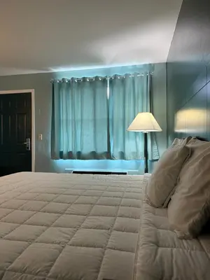 a bedroom with a bed and a lamp and a window at Country Club Inn & Suites in Fostoria