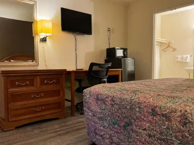 a hotel room with a bed and a dresser and a mirror at Country Club Inn & Suites in Fostoria