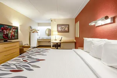 a hotel room with a large bed and a kitchen at Red Roof Inn Huntington in Barboursville