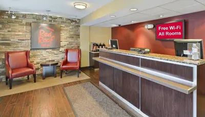 a bar with red chairs and a sign that reads free wifi all rooms at Red Roof Inn Huntington in Barboursville