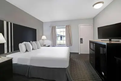 a hotel room with a white bed and a flat screen tv at Motel 6 Washington, PA in Washington