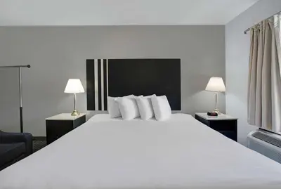 a large white bed in a hotel room with two lamps at Motel 6 Washington, PA in Washington