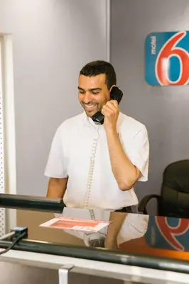 a man talking on a phone at a desk at Motel 6 Hurricane, WV in Hurricane
