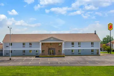 a large white building with a parking lot at Travel Inn Of Sidney Ohio in Sidney