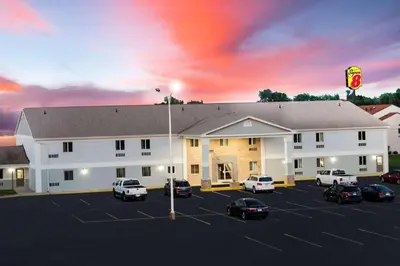 a hotel with cars parked in a parking lot at Travel Inn Of Sidney Ohio in Sidney