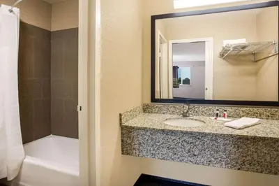 a bathroom with a sink and a mirror and a tub at Travel Inn Of Sidney Ohio in Sidney