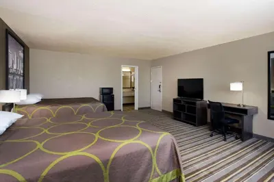 a hotel room with a bed and a desk and a television at Travel Inn Of Sidney Ohio in Sidney