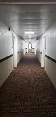 an empty hallway in an office building with a carpet at Travel Inn Of Sidney Ohio in Sidney