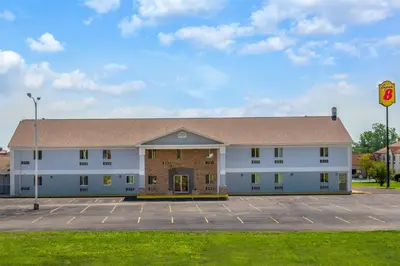 a large white building with a parking lot at Travel Inn Of Sidney Ohio in Sidney