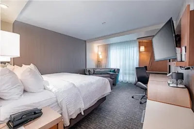 a hotel room with a bed and a flat screen tv at Courtyard by Marriott Toledo West in Toledo