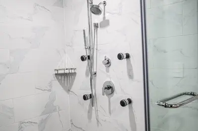a shower with a glass door with a shower head at Delta Hotels by Marriott Cincinnati Sharonville in Sharonville