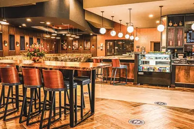 a kitchen with a bar with stools in it at Delta Hotels by Marriott Cincinnati Sharonville in Sharonville