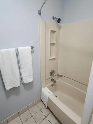 a bathroom with a tub and a shower with towels at WestSpring Inn - Westlake Cleveland in Westlake