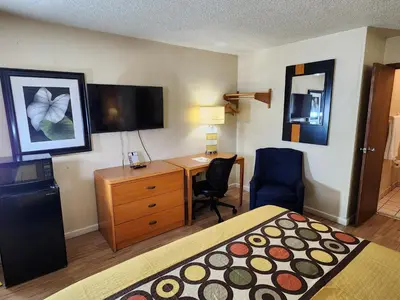a hotel room with a bedroom with a bed and a desk at WestSpring Inn - Westlake Cleveland in Westlake