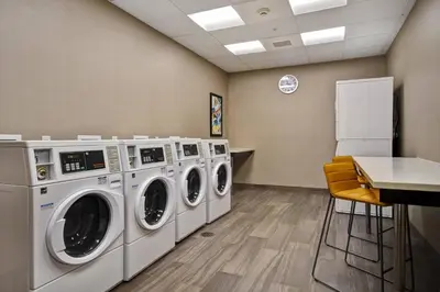 a laundry room with four washing machines and a table at Residence Inn by Marriott Cincinnati Northeast/Mason in Mason