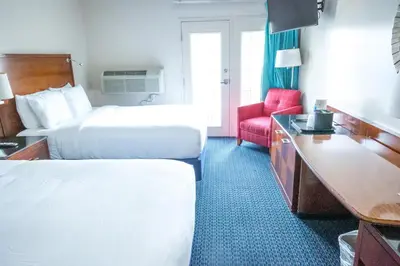 a hotel room with two beds and a red chair at Islander Inn in Put-in-Bay