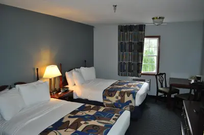 a hotel room with two beds and a desk at Grand Islander Hotel in Put-in-Bay